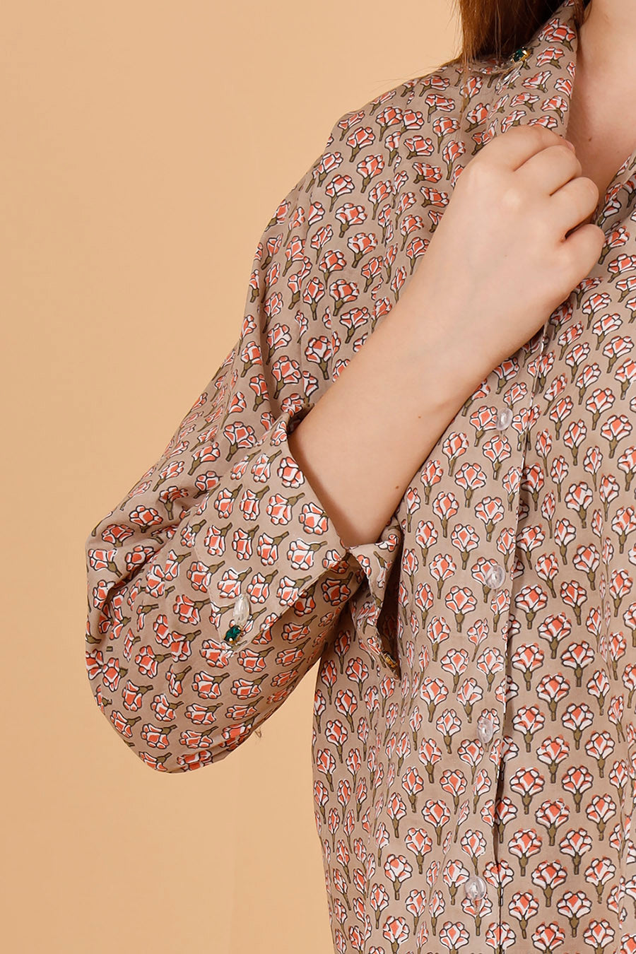 Details of a beautifully blockprinted embellished chic cotton blouse, with white trousers.